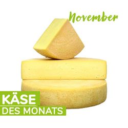 KI generiert: Das Bild zeigt mehrere Käselaibe, von denen einer angeschnitten ist, mit der Aufschrift "Käse des Monats November". Der Hauptinhalt ist die Präsentation eines Käses als Monatsempfehlung.