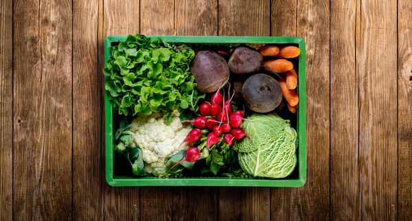 KI generiert: Eine grüne Kiste mit frischem Gemüse: Salat, Rote Bete, Möhren, Blumenkohl, Radieschen und Kohl.
