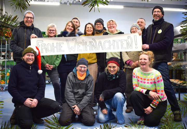 Das Team vom Lebendigen Land mit Plakat mit der Aufschrift "Frohe Weihnachten"