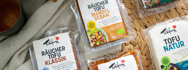 KI generiert: Das Bild zeigt eine Schüssel mit einer cremigen Suppe, garniert mit Kräutern und einigen Pilzen. Im Hintergrund liegen weitere Zutaten wie schwarzwurzelähnliches Gemüse, Kartoffeln und Schalotten.