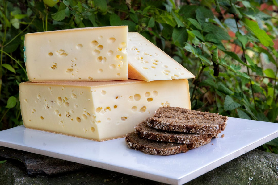 KI generiert: Ein Käseblock mit Löchern und geschnittenem Brot auf einer Platte.