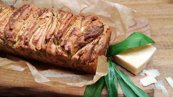 KI generiert: Ein frisch gebackenes, gefaltetes Brot mit Kräutern und Käse auf einem Holzbrett.