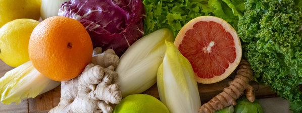 KI generiert: Frisches Obst und Gemüse, darunter Orange, Zitrone, Radicchio und Endivien auf einem Holzuntergrund.