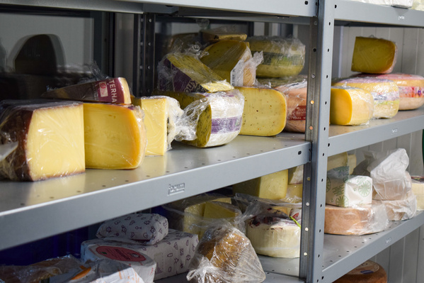 KI generiert: Regale mit verschiedenen Käsesorten, teilweise in Plastik verpackt.