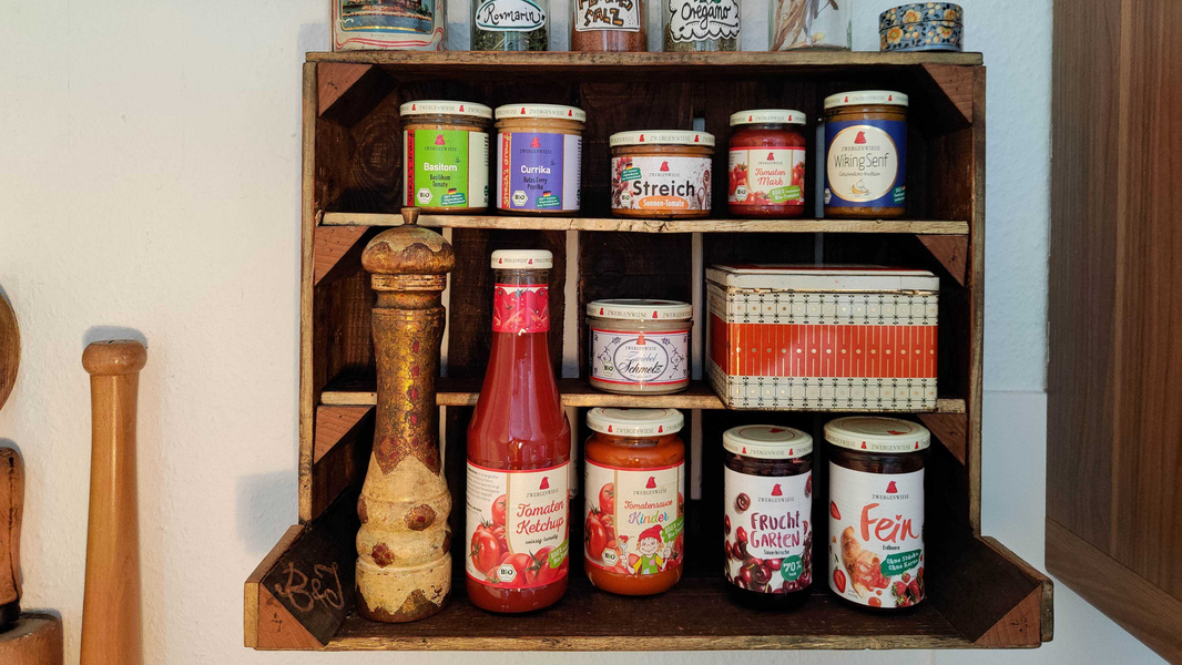 KI generiert: Ein Holzregal mit verschiedenen Gläsern und Flaschen von Aufstrichen und Gewürzen.