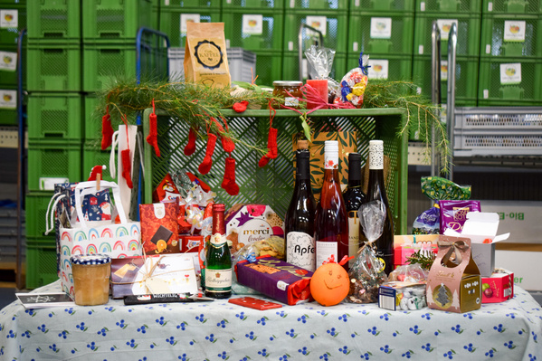 KI generiert: Ein Tisch mit verschiedenen Geschenkartikeln: Wein, Süßigkeiten, Deko.