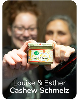 KI generiert: Zwei Personen halten ein Glas "Cashew Schmelz". Text: "Louise & Esther Cashew Schmelz".