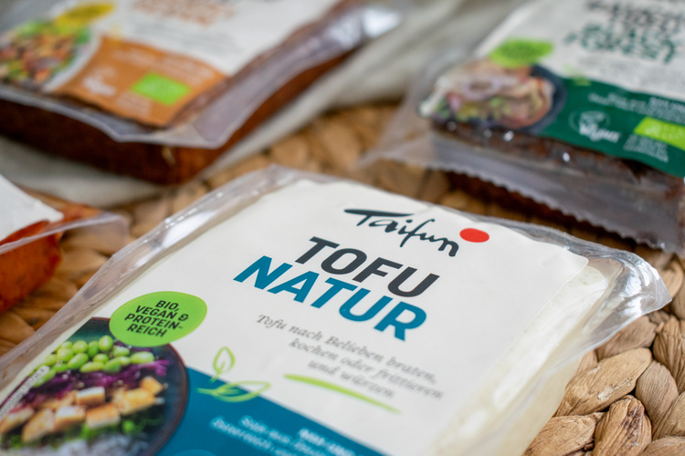 KI generiert: Verpackungen von Bio-Tofu-Produkten, im Vordergrund: "Taifun Tofu Natur".