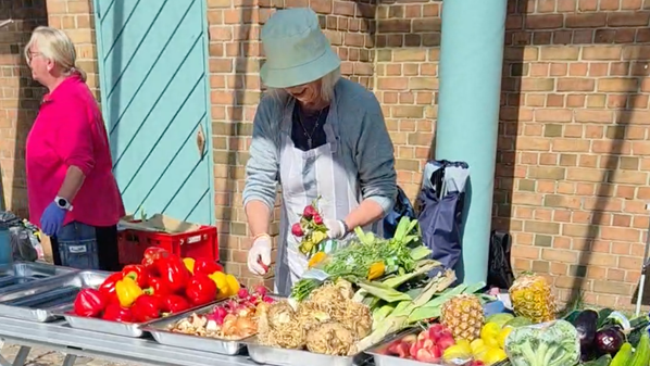 KI generiert: Marktszene: Zwei Personen an einem Stand mit frischem Gemüse und Obst.