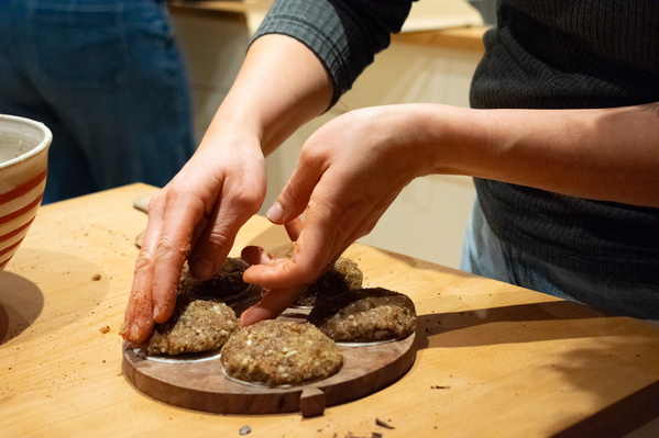 KI generiert: Eine Person formt mit den Händen vegane Burger-Patties auf einem Holztisch.