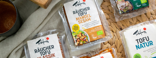 KI generiert: Das Bild zeigt eine Schüssel mit einer cremigen Suppe, garniert mit Kräutern und einigen Pilzen. Im Hintergrund liegen weitere Zutaten wie schwarzwurzelähnliches Gemüse, Kartoffeln und Schalotten.