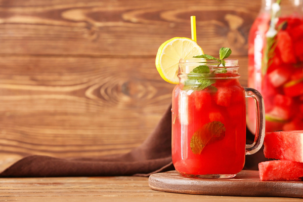 KI generiert: Ein Glas Wassermelonengetränk mit Zitrone und Minze auf einem Holzbrett.