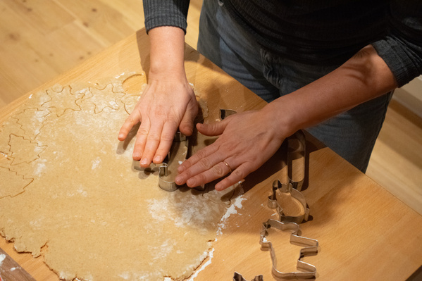 KI generiert: Eine Person verwendet Plätzchenausstecher auf ausgerolltem Teig.