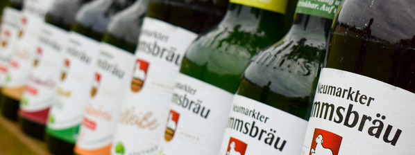 KI generiert: Flaschen mit dem Etikett "Neumarkter Lammsbräu" sind in einer Reihe angeordnet.