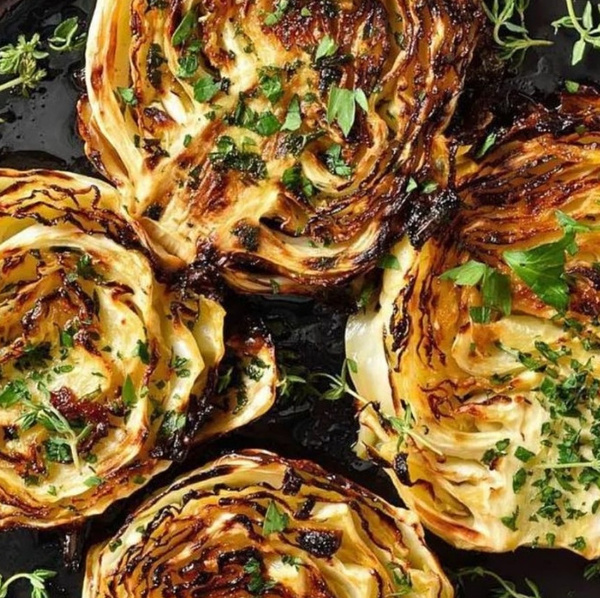 KI generiert: Geröstete Kohlscheiben mit Kräutern auf einem schwarzen Teller.