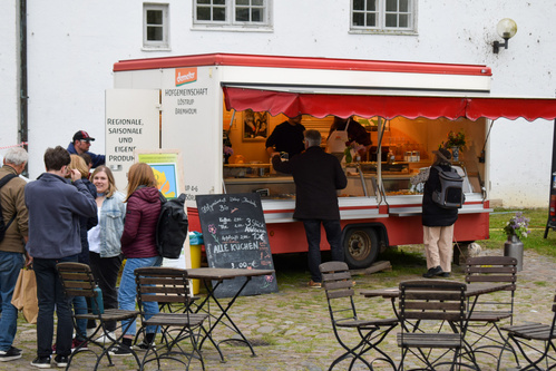 KI generiert: Ein Verkaufsstand mit wartenden Kunden und einem Angebotsschild: "Alle Kuchen 3,00€".