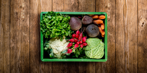 KI generiert: Kiste mit frischem Gemüse: Salat, Blumenkohl, Radieschen, Rote Beete, Karotten, Wirsing auf Holzhintergrund.