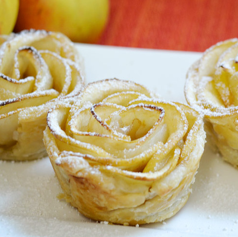 KI generiert: Blätterteiggebäck in Form von Rosen, mit Puderzucker bestäubt.