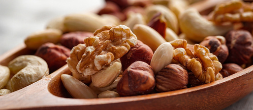 KI generiert: Eine Nahaufnahme von verschiedenen Nüssen in einer Holzschale.