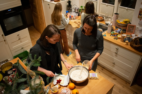 KI generiert: Menschen backen in einer gemütlichen Küche. Zutaten und Gebäck sind auf den Arbeitsflächen verteilt.