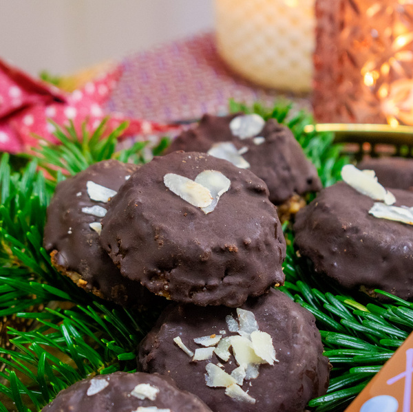 KI generiert: Schokoladenplätzchen mit Mandeln auf grünen Tannenzweigen arrangiert.