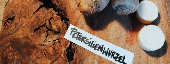 KI generiert: Das Bild zeigt eine Schüssel mit einer cremigen Suppe, garniert mit Kräutern und einigen Pilzen. Im Hintergrund liegen weitere Zutaten wie schwarzwurzelähnliches Gemüse, Kartoffeln und Schalotten.