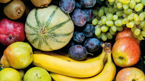 KI generiert: Gemischte Früchte: Kiwis, Trauben, Äpfel, Melone, Bananen, Birnen, Pflaumen und Granatapfel in Nahaufnahme.