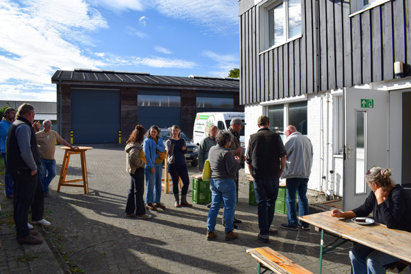 KI generiert: Eine Gruppe von Menschen steht und sitzt draußen bei einer Veranstaltung.