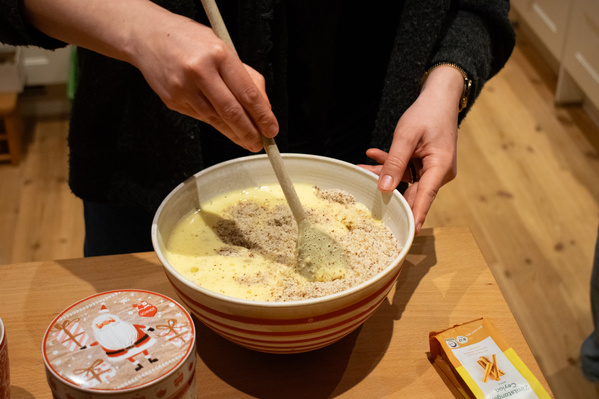 KI generiert: Person rührt Teig in Schüssel; daneben Dose mit Weihnachtsmotiv und Zimtstange.