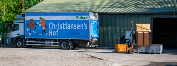 KI generiert: Ein LKW von "Christiansen's Hof" wird beladen. Text: "Bioland, Christiansen's Hof".