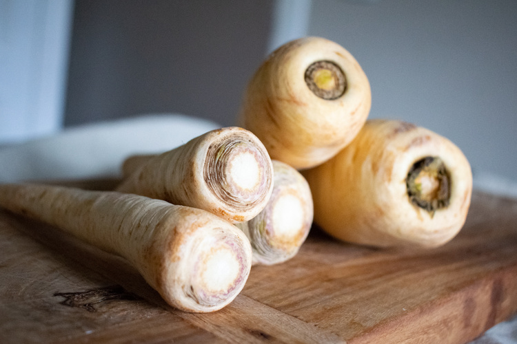 Petersilienwurzeln und Pastinaken auf einem Holzbrett