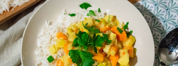 KI generiert: Das Bild zeigt eine Schüssel mit einer cremigen Suppe, garniert mit Kräutern und einigen Pilzen. Im Hintergrund liegen weitere Zutaten wie schwarzwurzelähnliches Gemüse, Kartoffeln und Schalotten.