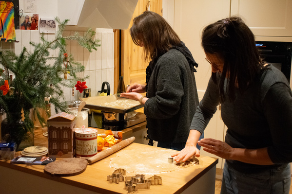 KI generiert: Zwei Personen backen Plätzchen in einer weihnachtlich dekorierten Küche.