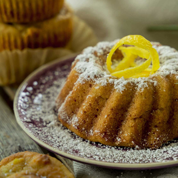 KI generiert: Ein Gugelhupf mit Puderzucker und Zitronenschale auf einem Teller.