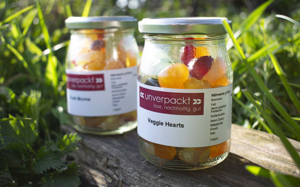 KI generiert: Zwei Gläser mit Süßigkeiten. Auf einem steht: „unverpackt, Veggie Hearts, lose, nachhaltig, gut“.