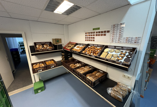 KI generiert: Ein Raum mit Regalen voller Brot und Gebäck. Schilder und Fotos an der Wand.