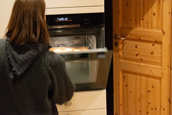 KI generiert: Eine Person öffnet einen Ofen mit Keksen. Display zeigt "00:01 160".